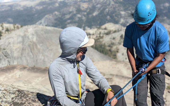 an instructor gives direction to a student preparing to rock climb on an outward bound trip